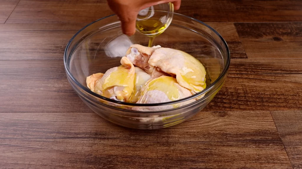 adding olive oil to chicken thighs