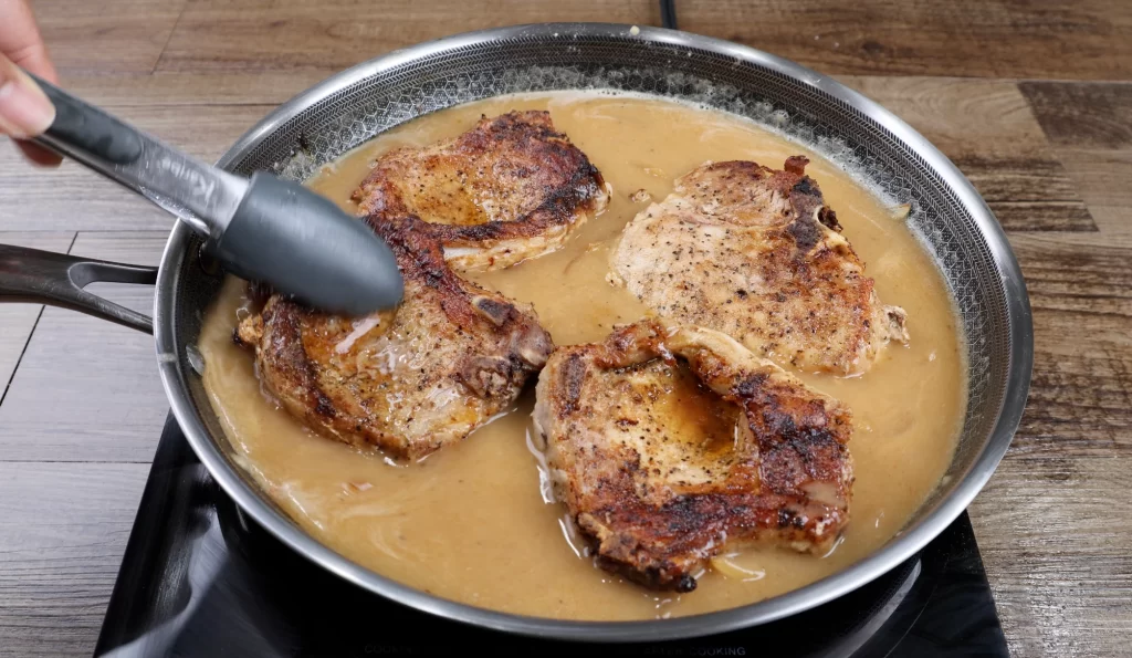 Returning pork chops to gravy to simmer